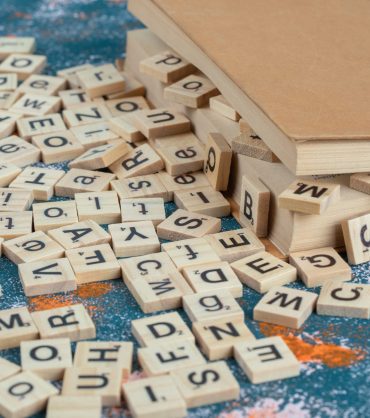 Wooden dice with letters on them between the pages of a book. High quality photo